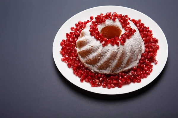 Kuchen mit Zuckerpuder und Granat auf blauem Hintergrund. traditionelle Ringkuchen für ein Café-Dessert. Süßwarenkonzept. — Stockfoto