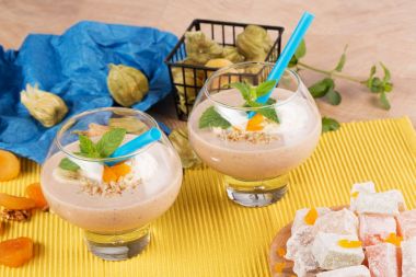 Kuru Kayısı, ceviz, nane yaprağı, renkli arka plan üzerinde physalis ile süslenmiş kokteyller iki bardak.