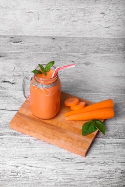 A fresh detox smoothie cocktail on a gray table background. A healthy carrot beverage in a mason jar. Copy space. clipart