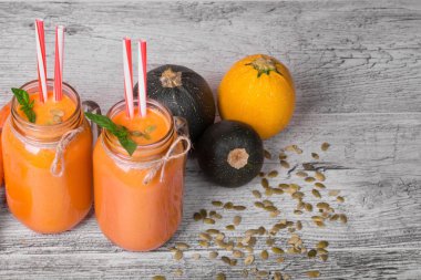 Üstten Görünüm bir güler yüzlü koca bir mason kavanoza iç. Havuç içecek gri bir arka plan üzerinde üç kabakları ile yenileme.