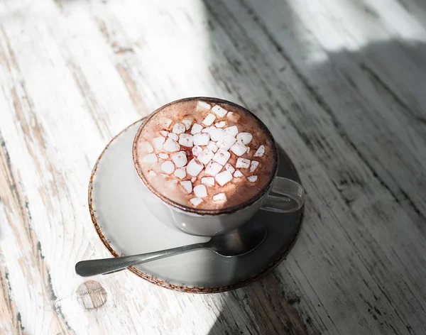 Eine schöne Tasse Milchkaffee mit Marshmallows auf grauem Holzgrund. ein Kakaogetränk in einer Porzellantasse. — Stockfoto