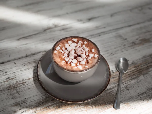 Uma bela xícara de café com leite marshmallows em um fundo de madeira cinza. Uma bebida de cacau em um copo de porcelana . — Fotografia de Stock