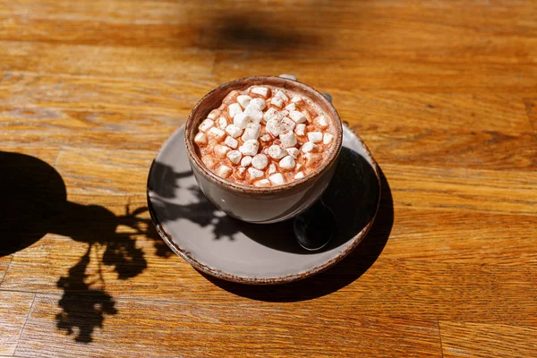 Uma vista superior de uma xícara de café em um fundo de mesa de madeira escura. Um cappuccino doce com marshmallows. Espaço de cópia . — Fotografia de Stock