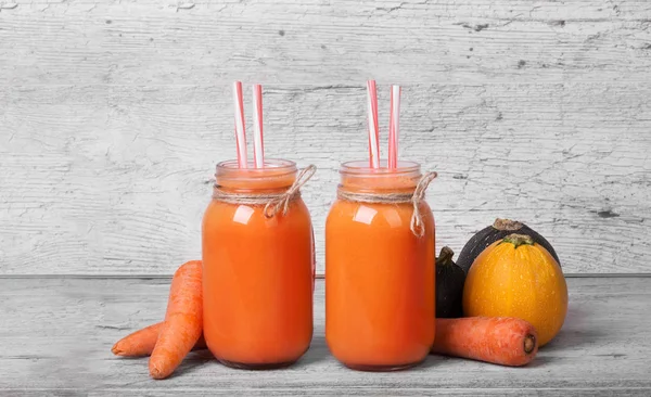 Büyük mason kavanoz birkaç güler yüzlü içki ile dolu. Çiğ havuç ve kabaklari gri bir arka plan üzerinde serinletici içecekler.