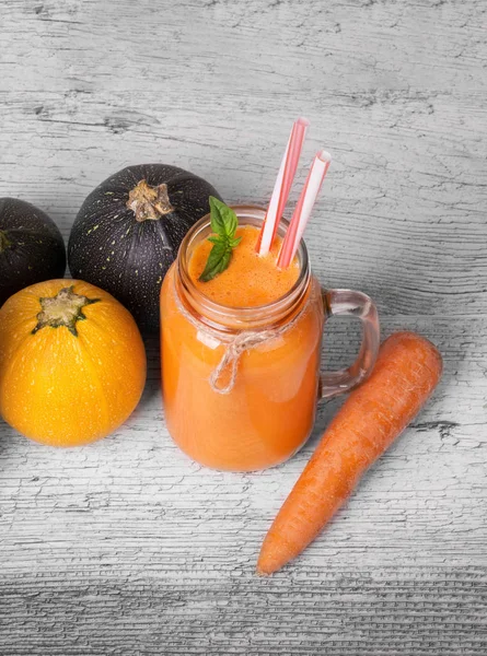 Sağlıklı malzemelerle parlak bir kompozisyonun en iyi görünümü gri bir arka plan üzerinde. Havuç suyu bir mason kavanoz. Detoks kavramı.