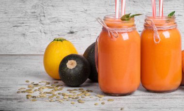 Serinletici içecekler çiğ parlak sağlıklı sebze ile. İki renkli yüzlü kokteyller mason kavanoz ahşap arka plan üzerinde.