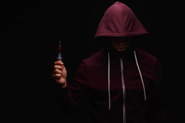 Uyuşturucu bağımlılığı bir koyu siyah arka plan üzerine kafasında bir kukuleta ile mor bir kazak bir uyuşturucu bağımlısı uğrar.