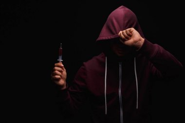 Uyuşturucu bağımlılığı bir koyu siyah arka plan üzerine kafasında bir kukuleta ile mor bir kazak bir uyuşturucu bağımlısı uğrar.