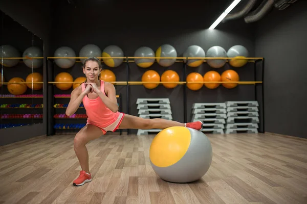 Sportlerin mit einem fitten Ball. Mädchen, das Beinstrecken auf einem verschwommenen Hintergrund macht. gesunder Lebensstil. Kopierraum. — Stockfoto