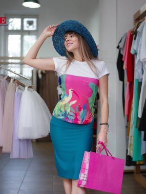 Mavi bir yaban domuzu ekledi şapka çekici bir Bayan giyim alışveriş arka plan üzerinde alışveriş yapar. Satış ve moda kavramı.