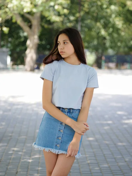 Een schattig jong meisje in casual kleding op een natuurlijke onscherpe achtergrond. Urban, mode en jeugd concept. Kopiëren van ruimte. — Stockfoto