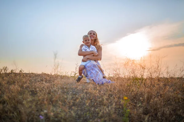 Um menino bonito e sua mãe em um fundo do céu. Uma família feliz juntos desfrutando de uma bela natureza. Espaço de cópia . — Fotografia de Stock