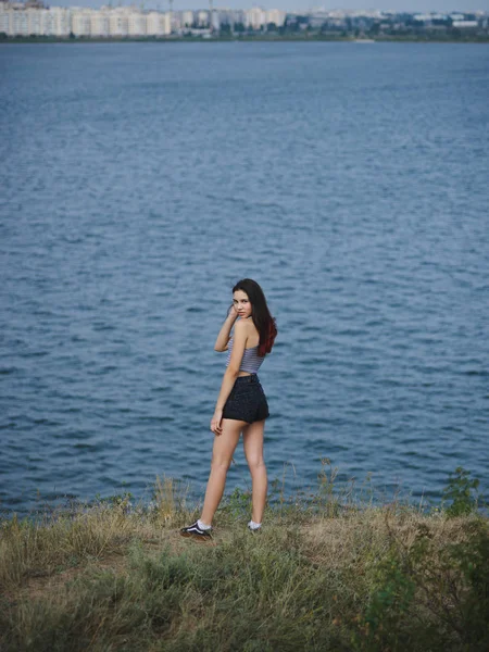 Menina em uma colina em um fundo natural turvo. Uma mulher gira, atraente e na moda. Conceito de viagem de jovens. Espaço de cópia . — Fotografia de Stock