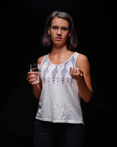 Dívka s painkiller v kapsli na černém pozadí. Pacientovi léky. Nemoc, nemoc, nemoci koncept. — Stock fotografie