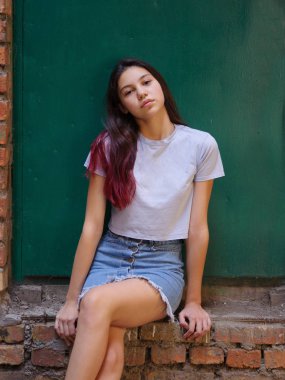 Bir portre rahat kıyafetler bir yeşil kapı arka plan üzerinde poz koyu saçlı güzel bir kız. Modaya uygun kentsel kavramı.