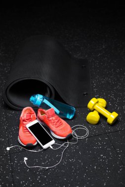 Spor ayakkabı, halter, şişe su ve telefon ile handphones bir siyah zemin zemin üzerine yakın çekim. Kopya alanı.