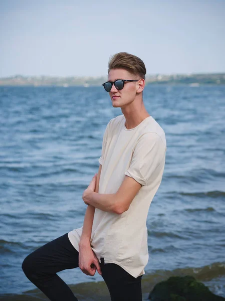 Um adolescente a relaxar perto do rio. Um rapaz casual ao ar livre com um fundo desfocado. Conceito de moda moderna. Espaço de cópia . — Fotografia de Stock