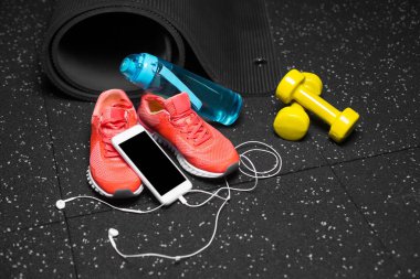 Spor ayakkabı, halter, şişe su ve telefon ile handphones bir siyah zemin zemin üzerine yakın çekim. Kopya alanı.