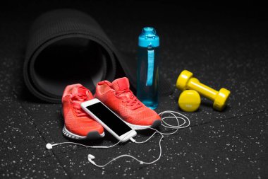 Spor ayakkabı, halter, şişe su ve telefon ile handphones bir siyah zemin zemin üzerine yakın çekim. Kopya alanı.