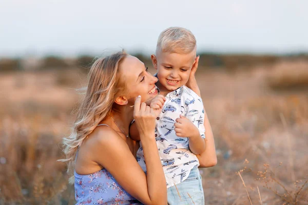 Foto de close-up de uma linda mulher brincando com seu filho bonito em um fundo de natureza turva. Ao ar livre. Espaço de cópia . — Fotografia de Stock