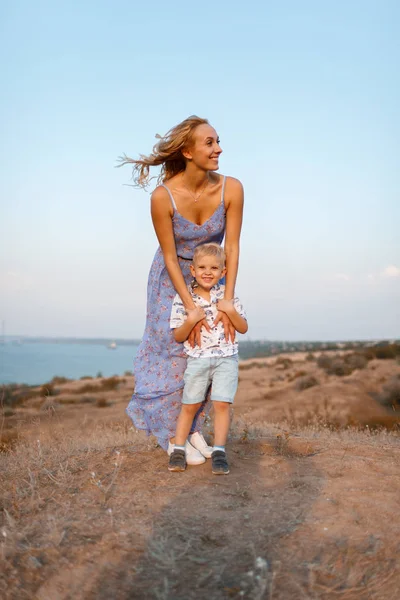 Uma mulher deslumbrante com seu filho em um fundo natural. Uma família feliz juntos. Maternidade e infância . — Fotografia de Stock