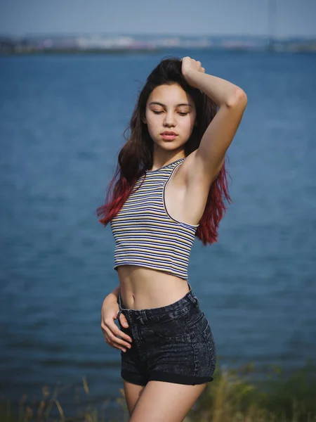 Sexy, schattig jong meisje aan haar haar te raken. Een tiener op een achtergrond wazig rivier. Schoonheid en stijl concept. Kopiëren van ruimte. — Stockfoto