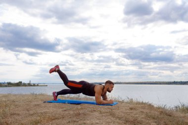 Anız ve bir tahta üzerinde doğal bir arka plan bulanık bir omuz ayakta bir dövme ile güçlü bir sporcu.