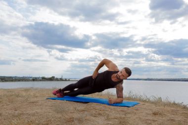 Anız ve bir tarafı tahta üzerinde doğal bir arka plan bulanık bir omuz ayakta bir dövme ile güçlü bir sporcu.