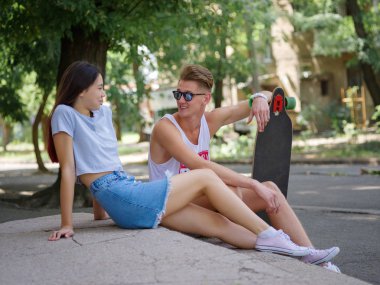 Güzel bir kız ve bir longboard taş doğal bir arka plan bulanık merdivenlerde oturan bir adam.