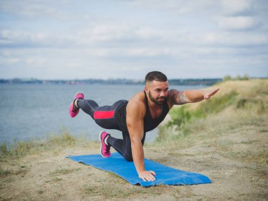 Pratik yoga açık havada muhteşem genç erkek portresi. Sabah güneşi altında dış eğitim.