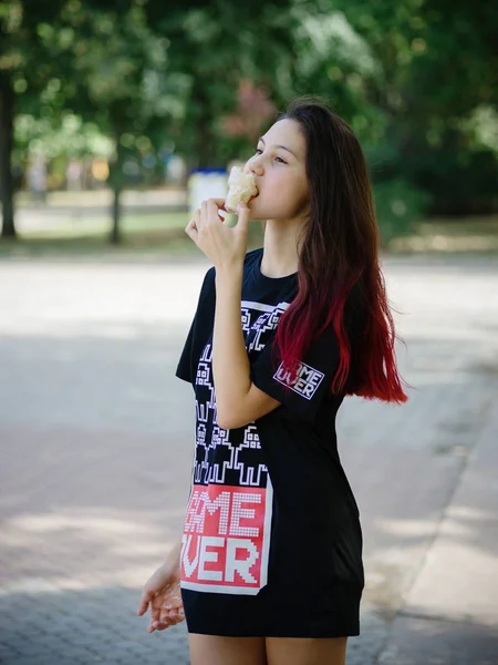 Een charmante, kleding mode hipster meisje in de zomer eten ijs op een stedelijke achtergrond. Mode stedelijk concept. Kopiëren van ruimte. — Stockfoto