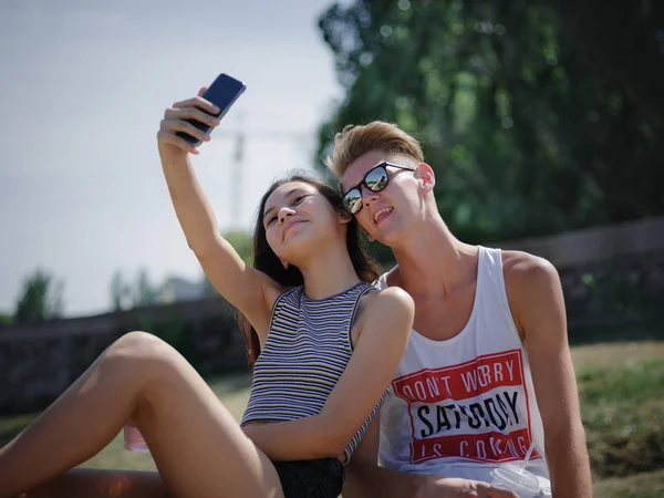 Happy smiling boy and girl on a park background. Boyfriend and girlfriend taking pictures. Progressive youth concept. — Stock Photo, Image