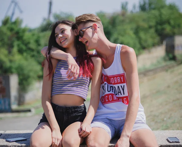 Laughing teenagers relaxing on a natural background. Romantic couple hugging in a city park. Young relationship concept. — Stock Photo, Image