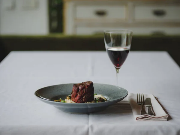 Skład kolacji na tle restauracja niewyraźne. Smaczne danie obok kieliszek czerwonego wina. Miejsce. — Zdjęcie stockowe