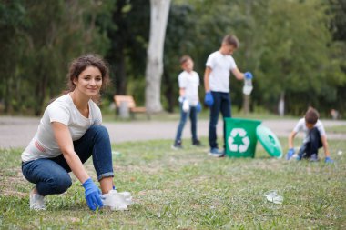 Bir bulanık park arka plan üzerinde plastik çöp toplama genç güzel bir kadın. Ekoloji kirliliği kavramı.