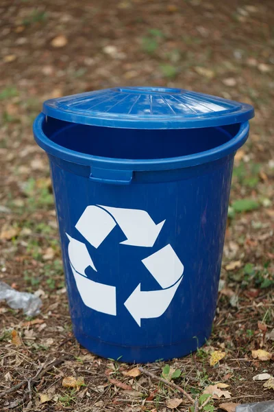 Recipiente de reciclaje azul oscuro sobre un fondo de tierra. Una papelera para el reciclaje de basura. Medio ambiente, ecología, concepto de reciclaje . — Foto de Stock