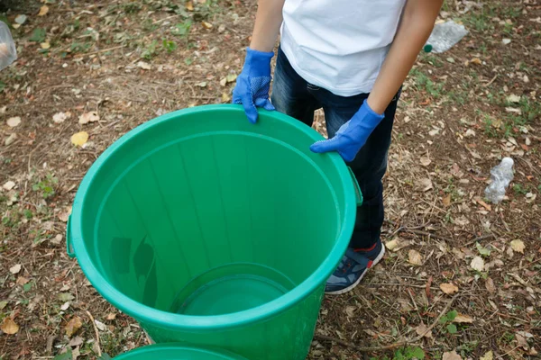 Papelera de reciclaje colorido con manos de niños en guantes de látex azul. Fuera de la foto, la tierra en el fondo . — Foto de Stock