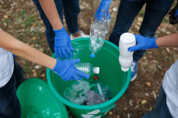 Barnens händer i blå latex handskar håller plastflaskor på park marken bakgrund. Ekologi skydd koncept. — Stockfoto