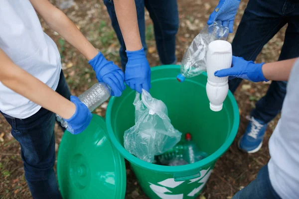 Barnens händer i blå latex handskar håller plastflaskor på park marken bakgrund. Ekologi skydd koncept. — Stockfoto