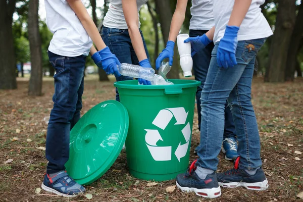 Close-up de crianças mãos em luvas de látex azul segurando lixo plástico em um fundo do parque turvo. Conceito de protecção ecológica . — Fotografia de Stock