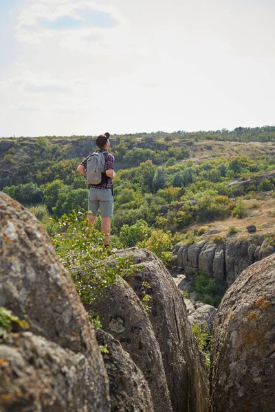 Junger Mann mit Rucksack, der auf dem Gipfel der Berge in die Ferne blickt. ein Tourist auf natürlichem Hintergrund. — Stockfoto