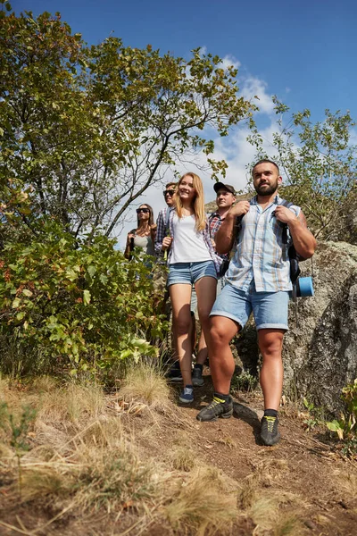 A group photo of young people having fun outdoors. A company of cheerful travelers on a blurred natural background. — Stock Photo, Image