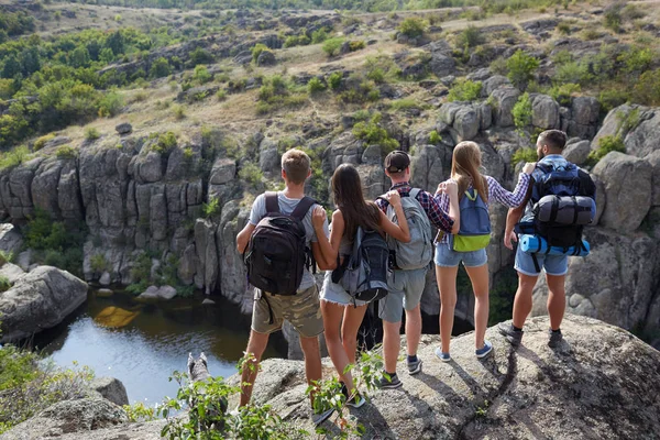 Jongeren staande op de heuvels. Een bedrijf van vrolijke reizigers op een onscherpe natuurlijke achtergrond. Kopiëren van ruimte. — Stockfoto