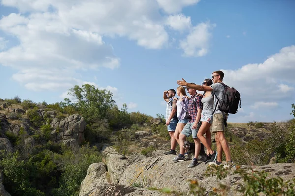 Jongeren staande op de heuvels. Een bedrijf van vrolijke reizigers op een onscherpe natuurlijke achtergrond. Kopiëren van ruimte. — Stockfoto