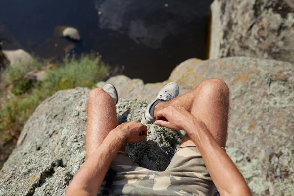 Benen van een reiziger zittend op een top van de berg buitenshuis. Selfie van benen op een onscherpe achtergrond van de natuurlijke. — Stockfoto