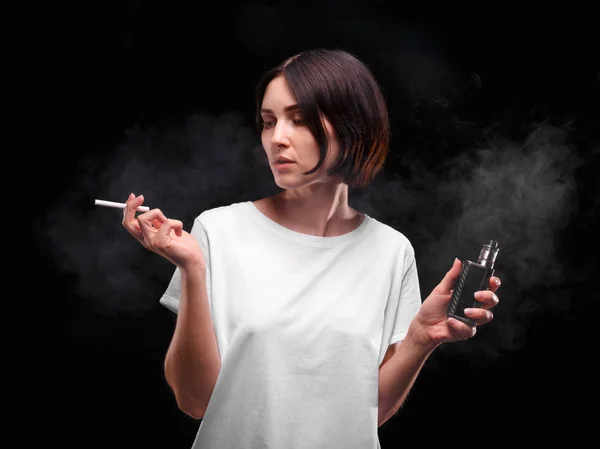 Bir kız sigara ve her iki elinde elektronik sigara portresi. Bir siluet ofd bir kadın siyah bir zemin üzerine. — Stok fotoğraf