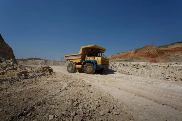 Zijaanzicht van een gele punt truck met een schaduw op een natuurlijke achtergrond. Grote vervoerder in een zanderige steengroeve. — Stockfoto