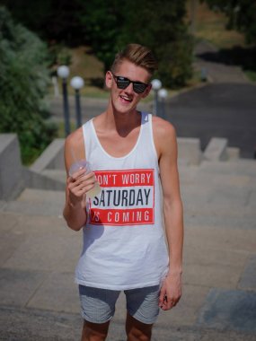 Gülümseyen genç bir adam ile bir limonata kentsel arka plan bulanık. Şık bir adam açık havada güneş gözlüğü. Kopya alanı.