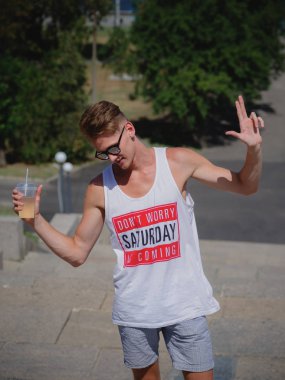 Serin uzun boylu genç bir erkekle bir limonata kentsel arka plan bulanık. Şık bir adam açık havada güneş gözlüğü.