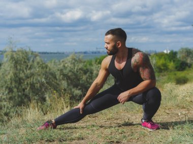 Çimlere ve doğal bir arka plana uzanan yakışıklı ve güçlü bir erkeğin tam boy fotoğrafı. Açık havada idman..